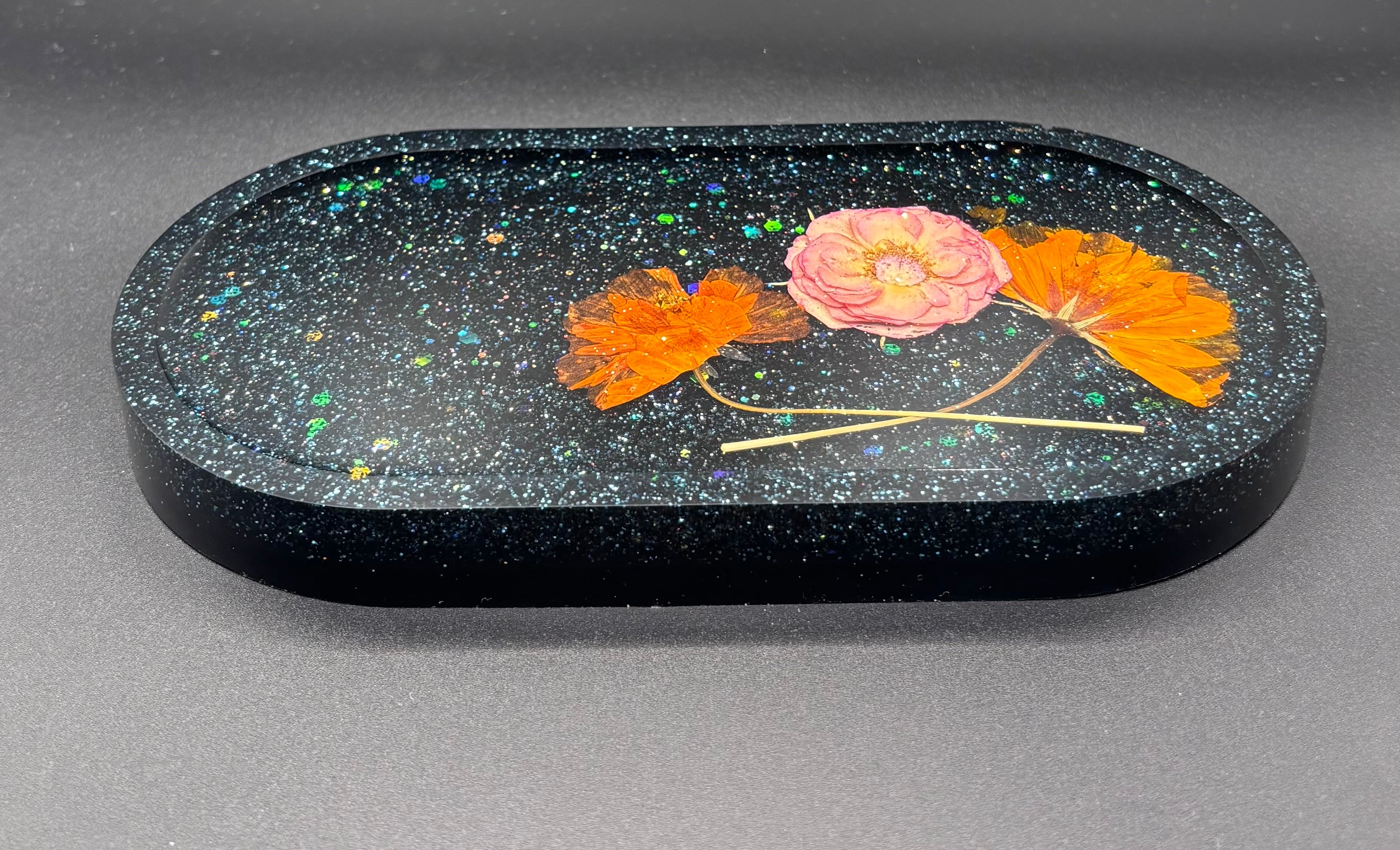 Black galaxy resin tray with holographic glitter and pressed flowers